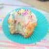 Vanilla protein cupcake with frosting and sprinkles on a blue cupcake liner with more cupcakes behind it.