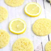 Thin dairy and gluten-free lemon cookies on parchment paper with lemons around them.