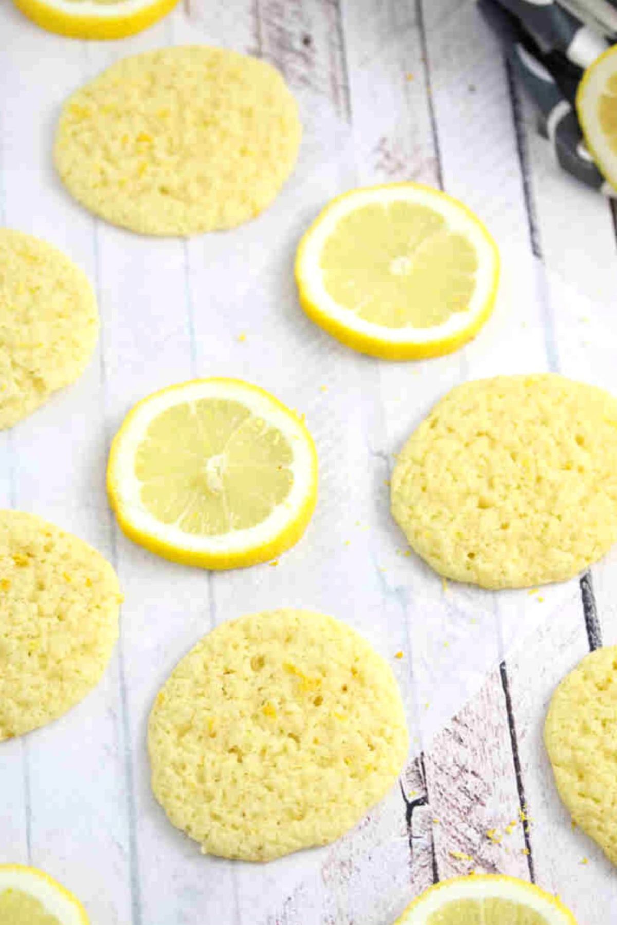 Thin dairy and gluten-free lemon cookies on parchment paper with lemons around them.