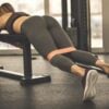Woman in the gym laying on a bench with a mini band around her knees.
