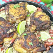 Gluten-free jerk chicken and rice in a cast iron skillet with limes on it