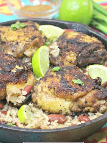 Gluten-free jerk chicken and rice in a cast iron skillet with limes on it