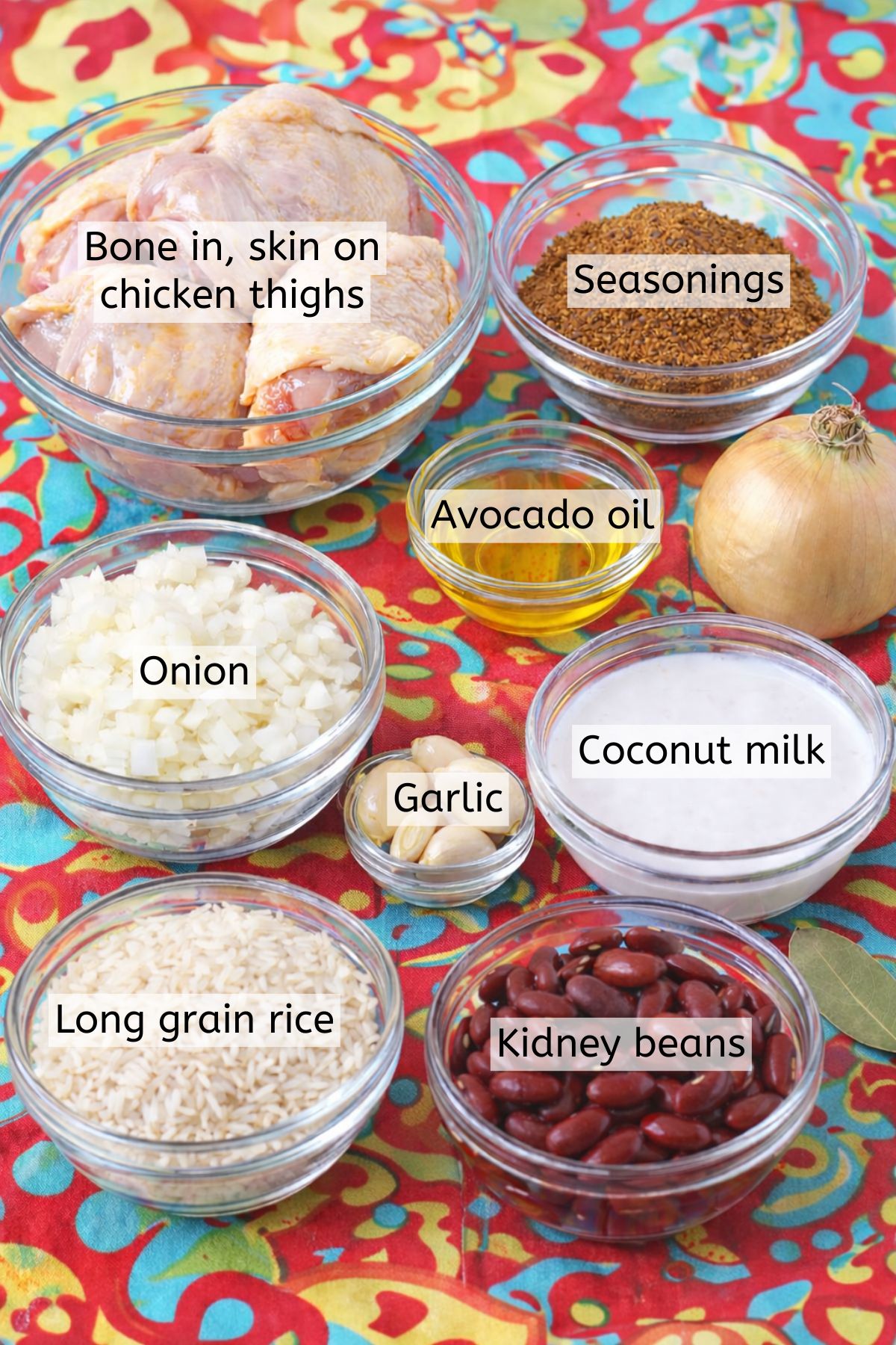 Multiple ingredients to make jerk chicken in glass bowls with text labels over top.