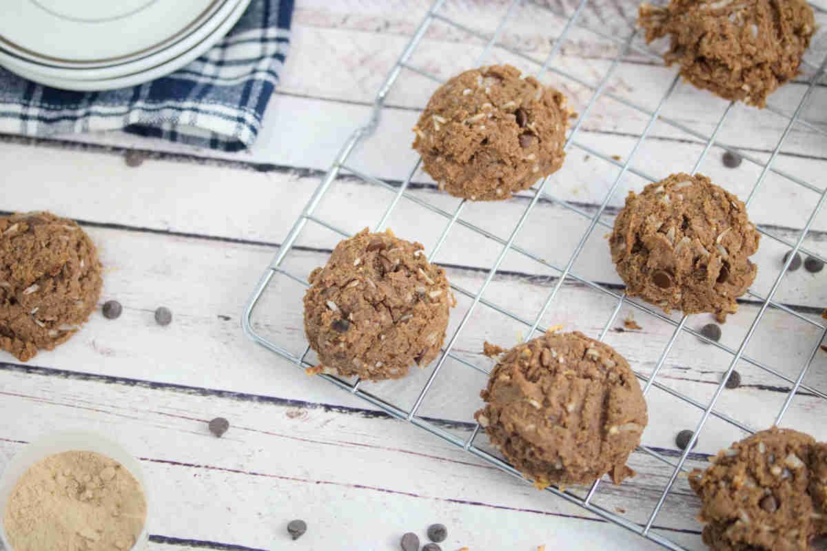 Chocolate vegan protein cookies on a cooling rack with ingredients around the rack