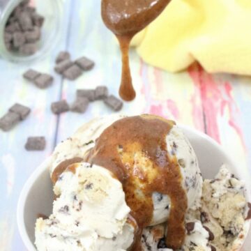 Caramel magic shell being drizzled onto dairy-free ice cream in a peach bowl with chocolate chips behind it.