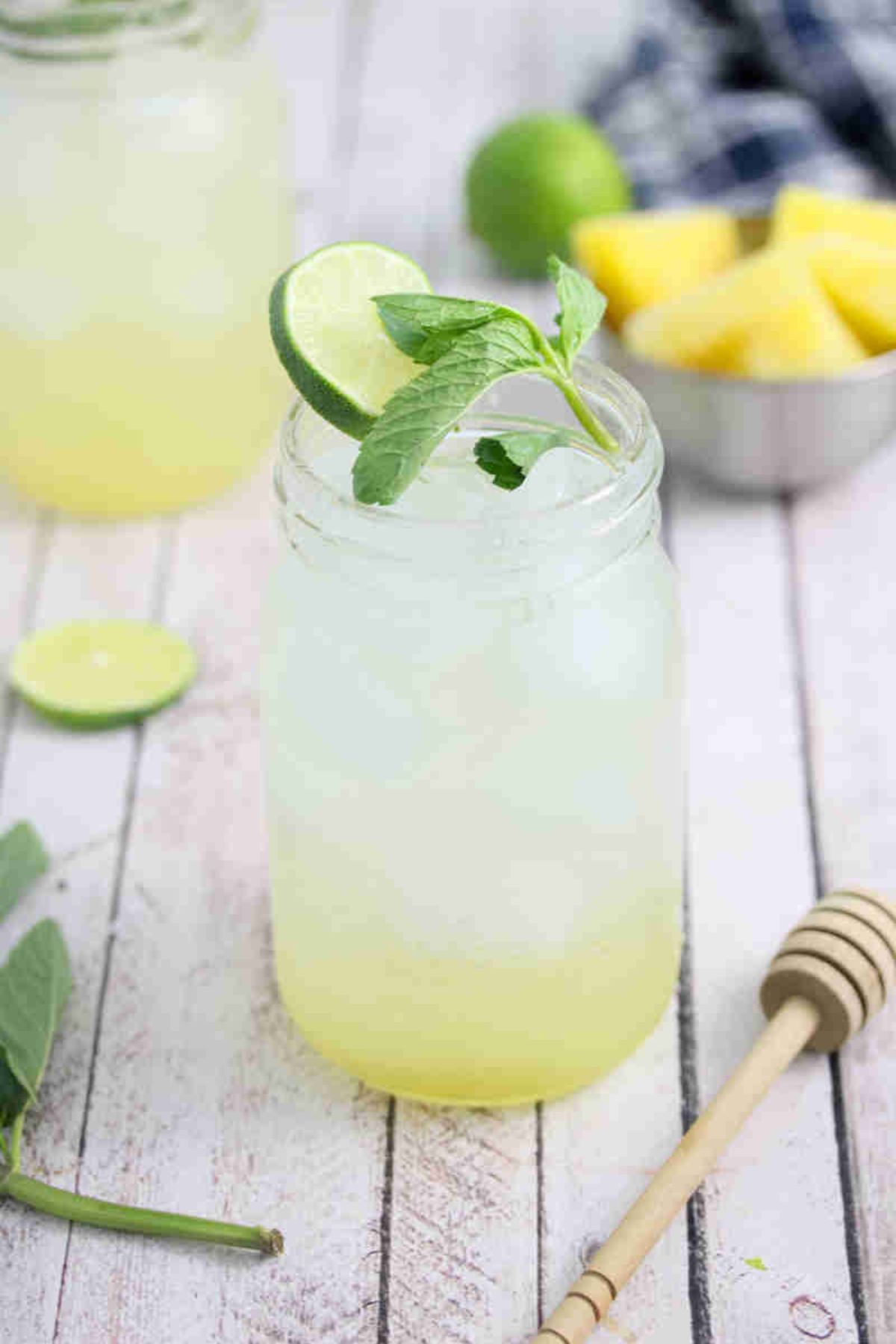 Ginger beer mocktail in a mason jar with fresh mint and lime on the jar and ingredients and another jar around it.
