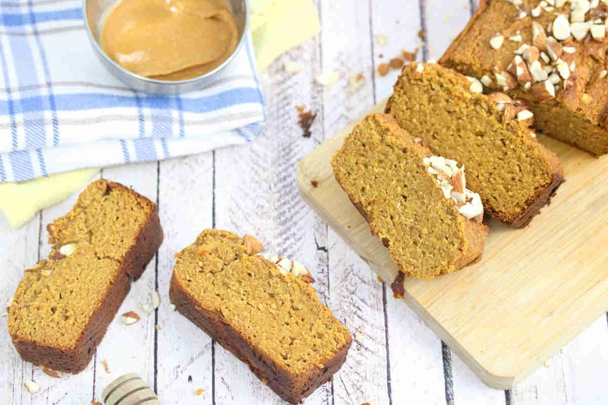 Healthy pumpkin bread in slices on a cutting board and around it with peanut butter on the side.