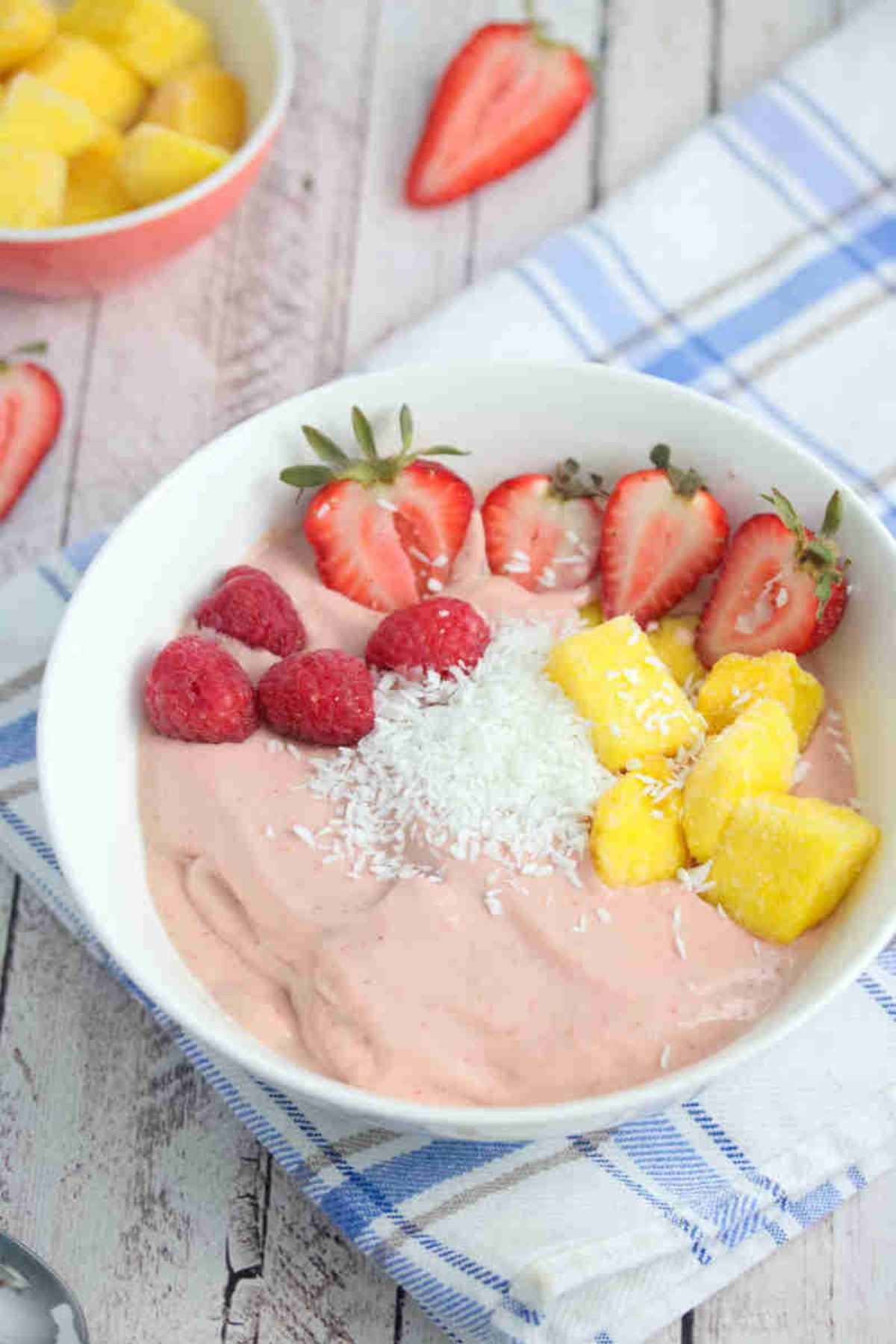 Strawberry smoothie bowl in a white bowl with fruit on it.