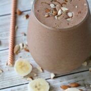 Chunky monkey protein shake with caramel drizzled on top and chopped almonds on the shake and around it.