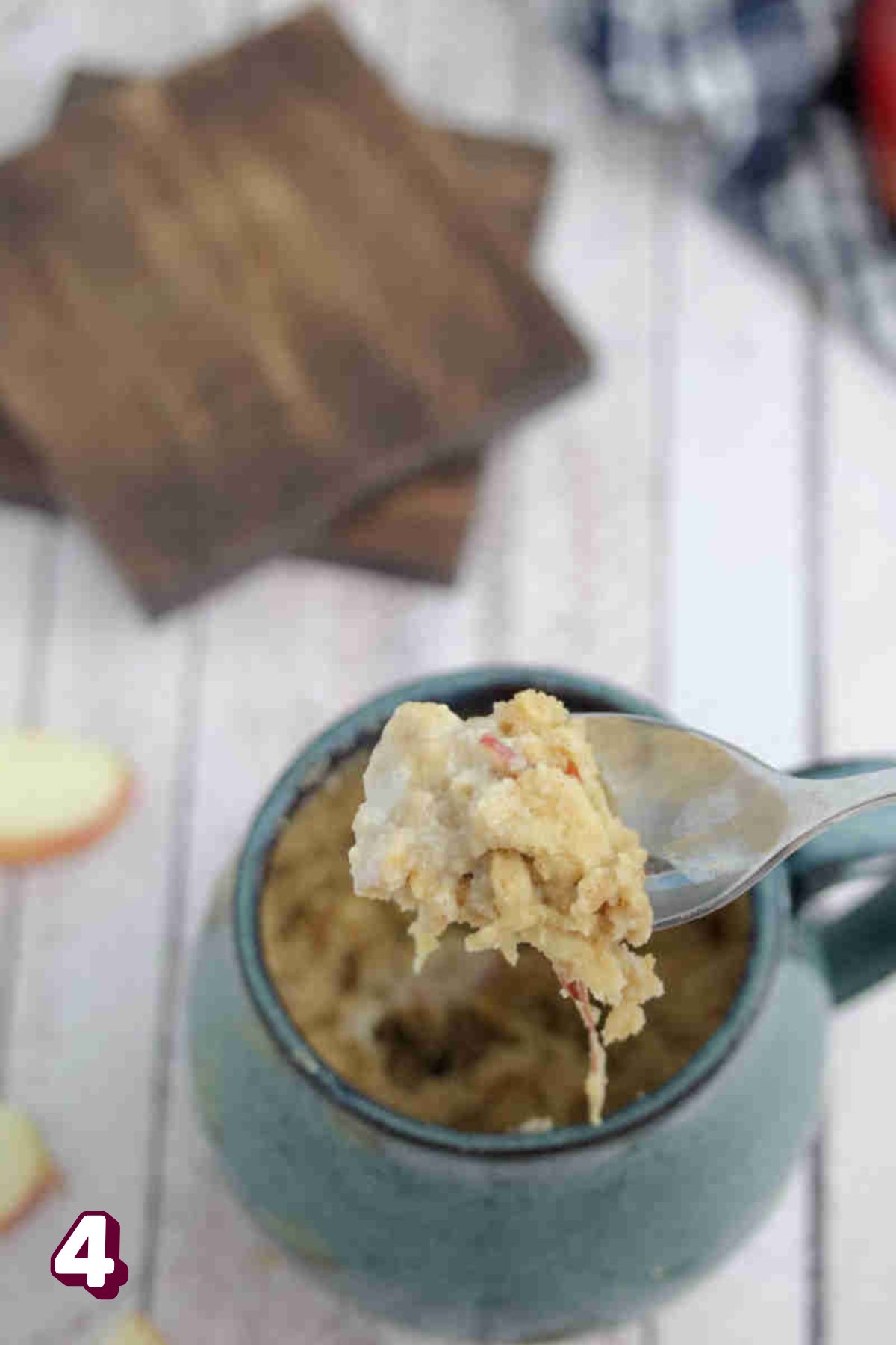 Blue mug with a spoon pulling out with apple cake on it.