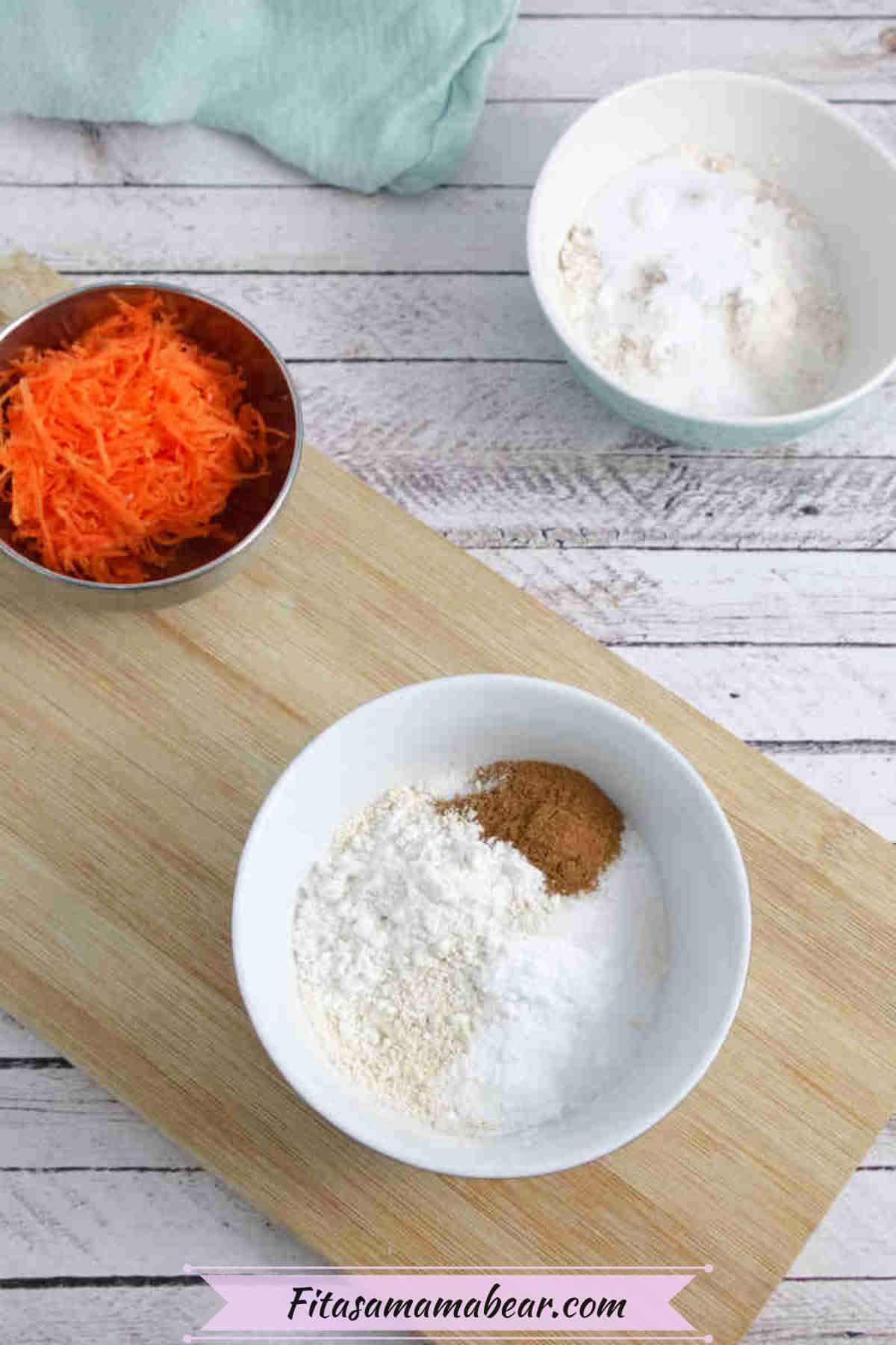 White bowl with flour and cinnamon on a wooden cutting board with grated carrot and more flour behind it.