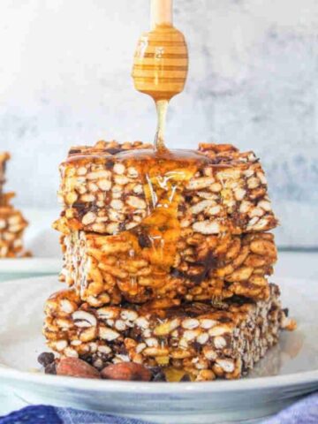 Honey drizzled onto rice crispy squares with chocolate chips in them.