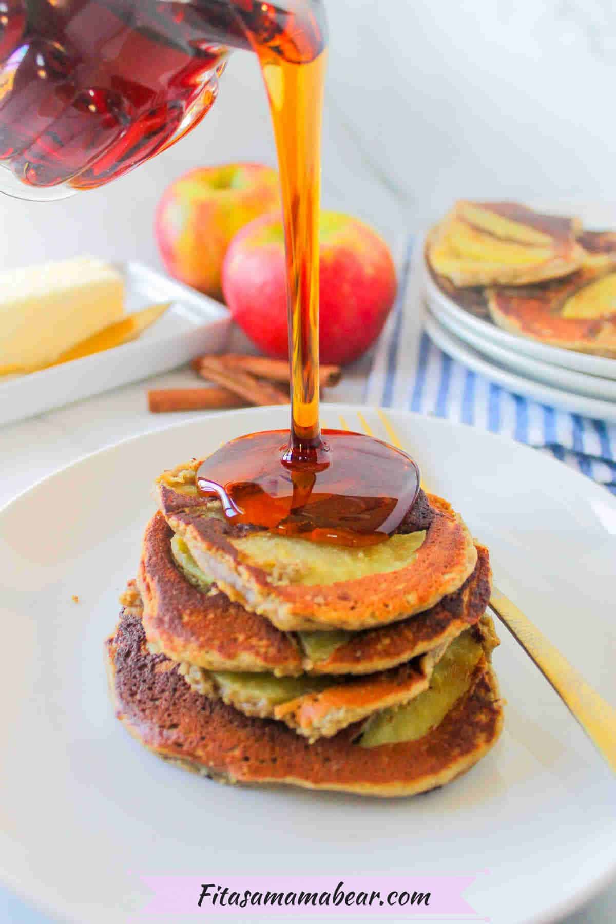 Syrup being poured onto protein pancakes on a white plate with a fork on it.
