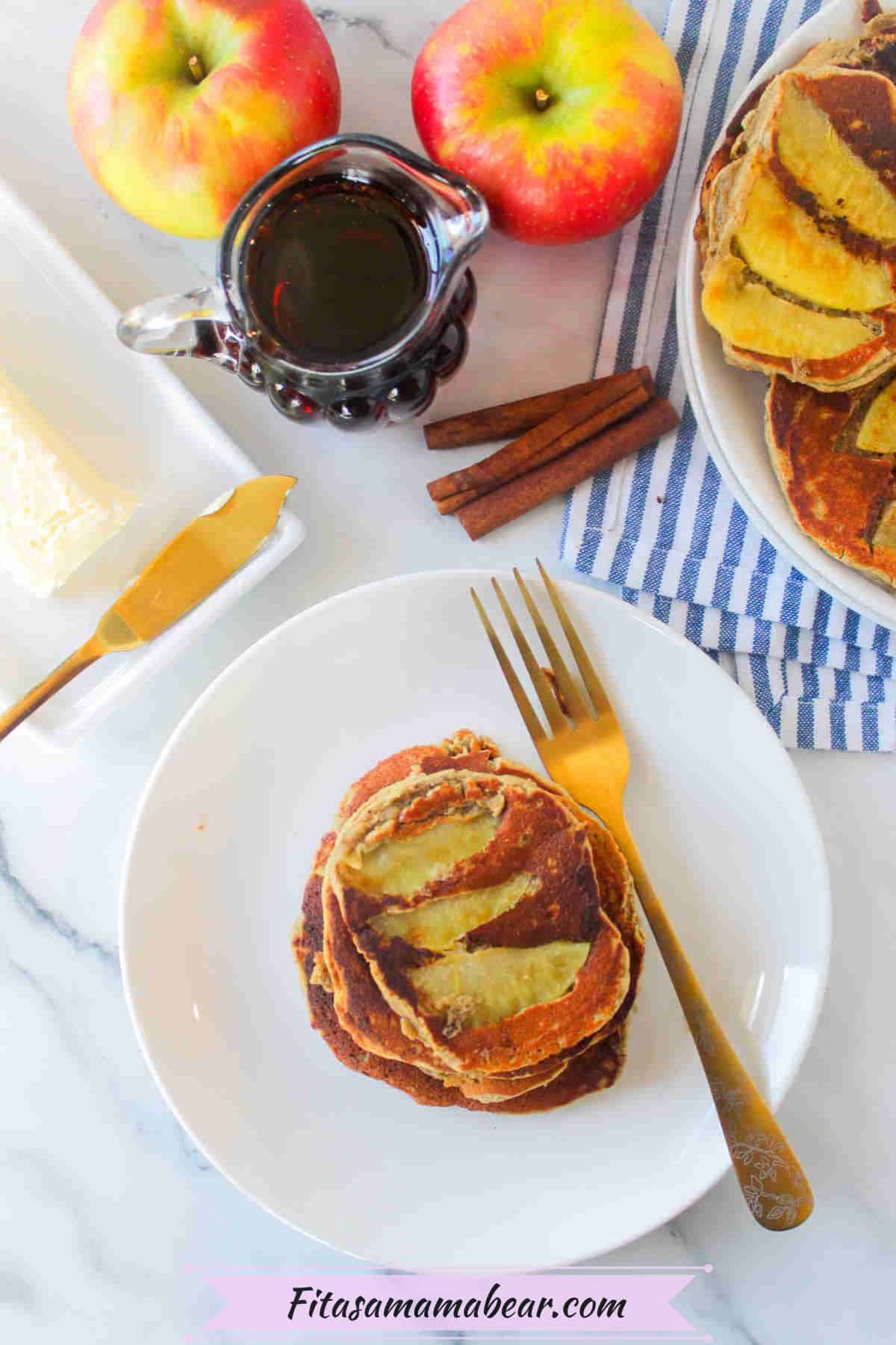 Apple cinnamon pancakes stacked on a white plate with a fork on it.