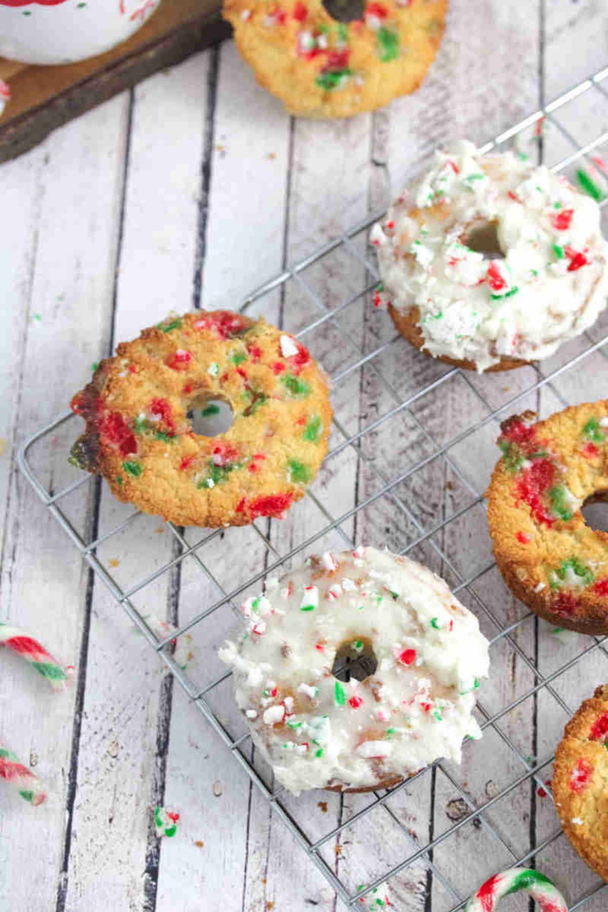 Candy cane donuts on a cooling rack some donuts frosted with glaze.