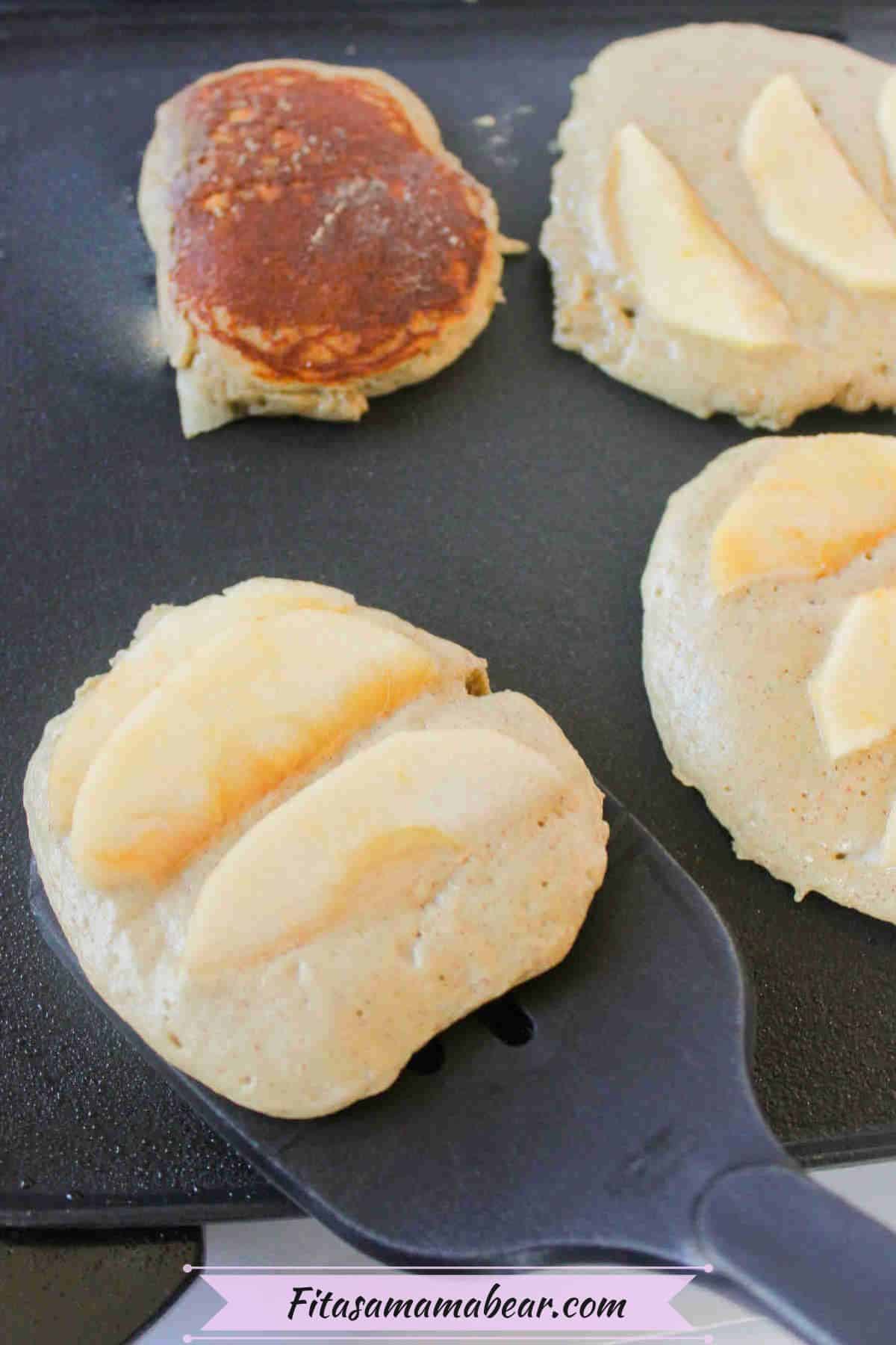 Apple pancake being flipped with a black spatula.