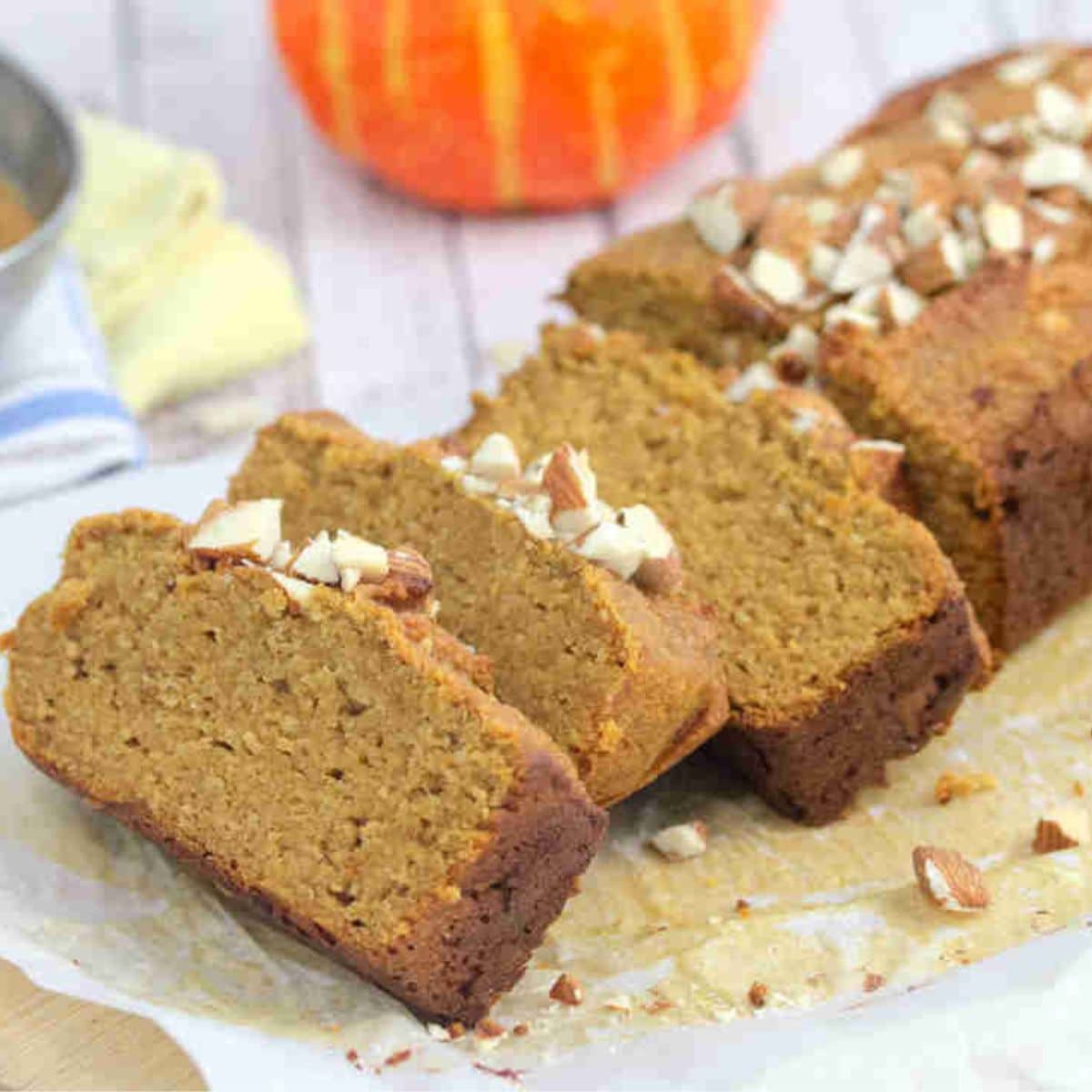 Protein pumpkin bread sliced and topped with almonds on a cutting board.
