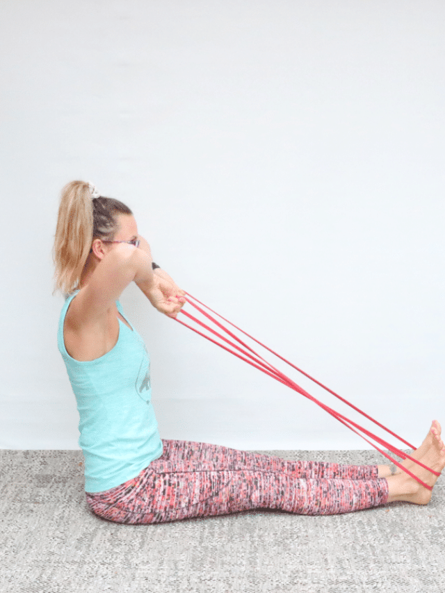 Woman in blue tank top and tights performing a face pull exercise with a resistance band.