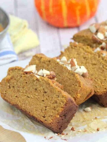 Protein pumpkin bread sliced and topped with almonds on a cutting board.
