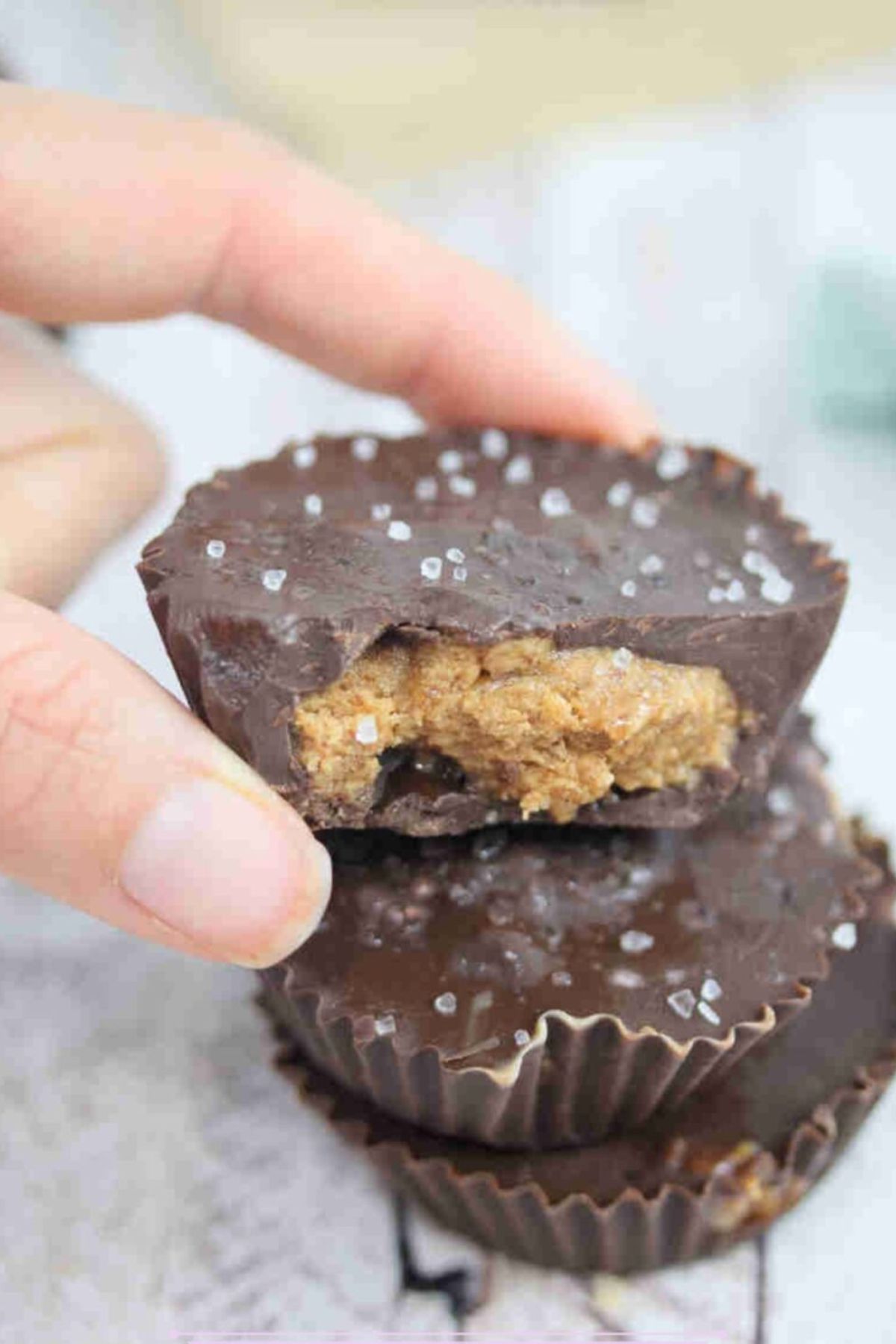 Fingers holding a chocolate almond butter protein cup on top of another.