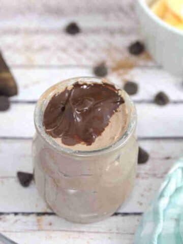 Chocolate protein pudding in a jar and chocolate sauce on top.