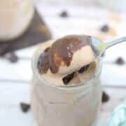 Chocolate protein pudding in a jar with chocolate sauce n top and a spoon in the jar.
