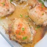 Honey and lemon baked chicken thighs with parsley on top in a baking dish.