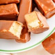 Chocolate coated Twix protein bars on a plate with one bar broken in half.