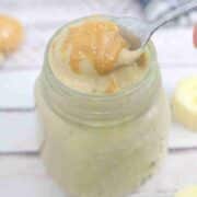 Banana protein pudding in a jar with peanut butter on top and a spoon in the jar.