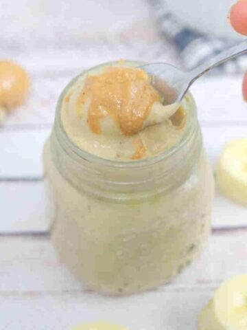 Banana protein pudding in a jar with peanut butter on top and a spoon in the jar.