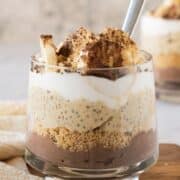 Chia pudding parfait in a glass layered with cookies, whipped cream, and bananas.