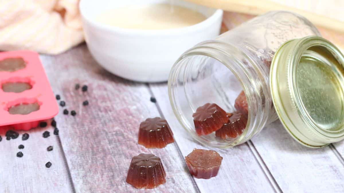 Elderberry cough drops in a tipped over jar with dried elderberries around them.