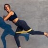 Woman in sports bra performing a glute exercise with a yellow mini loop.