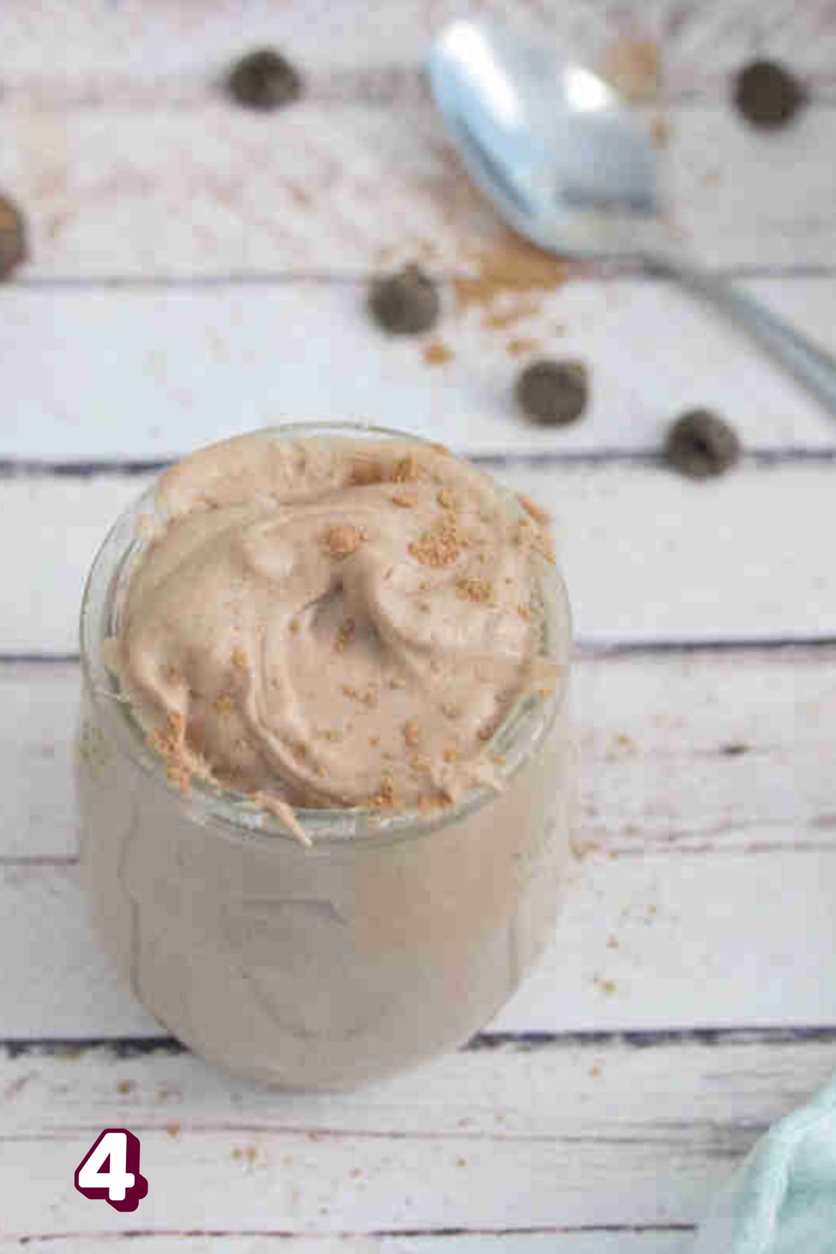 Chocolate protein pudding in a jar with cacao powder on top.