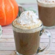 Pumpkin spice latte in a glass with whipped cream and cinnamon on top.