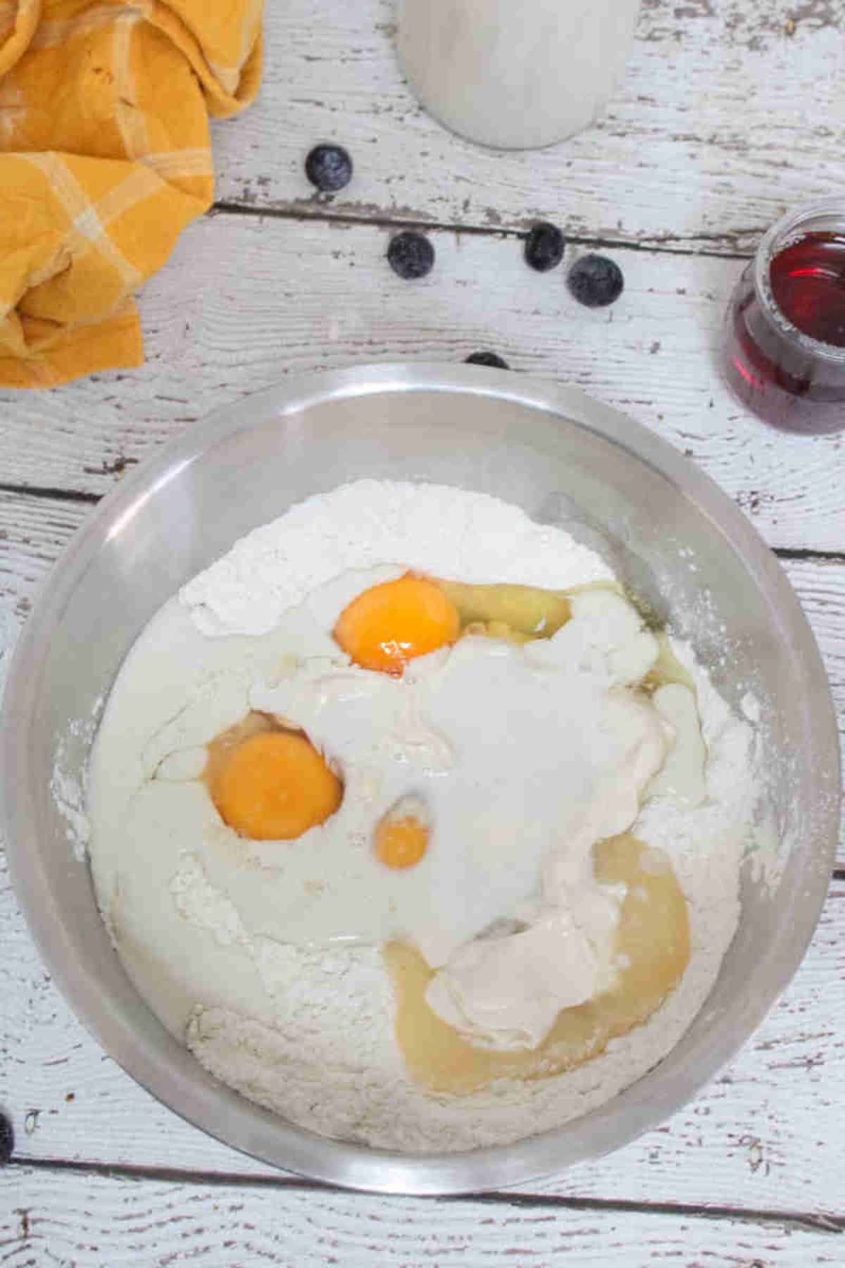 Eggs, flour, and milk in a steel bowl.
