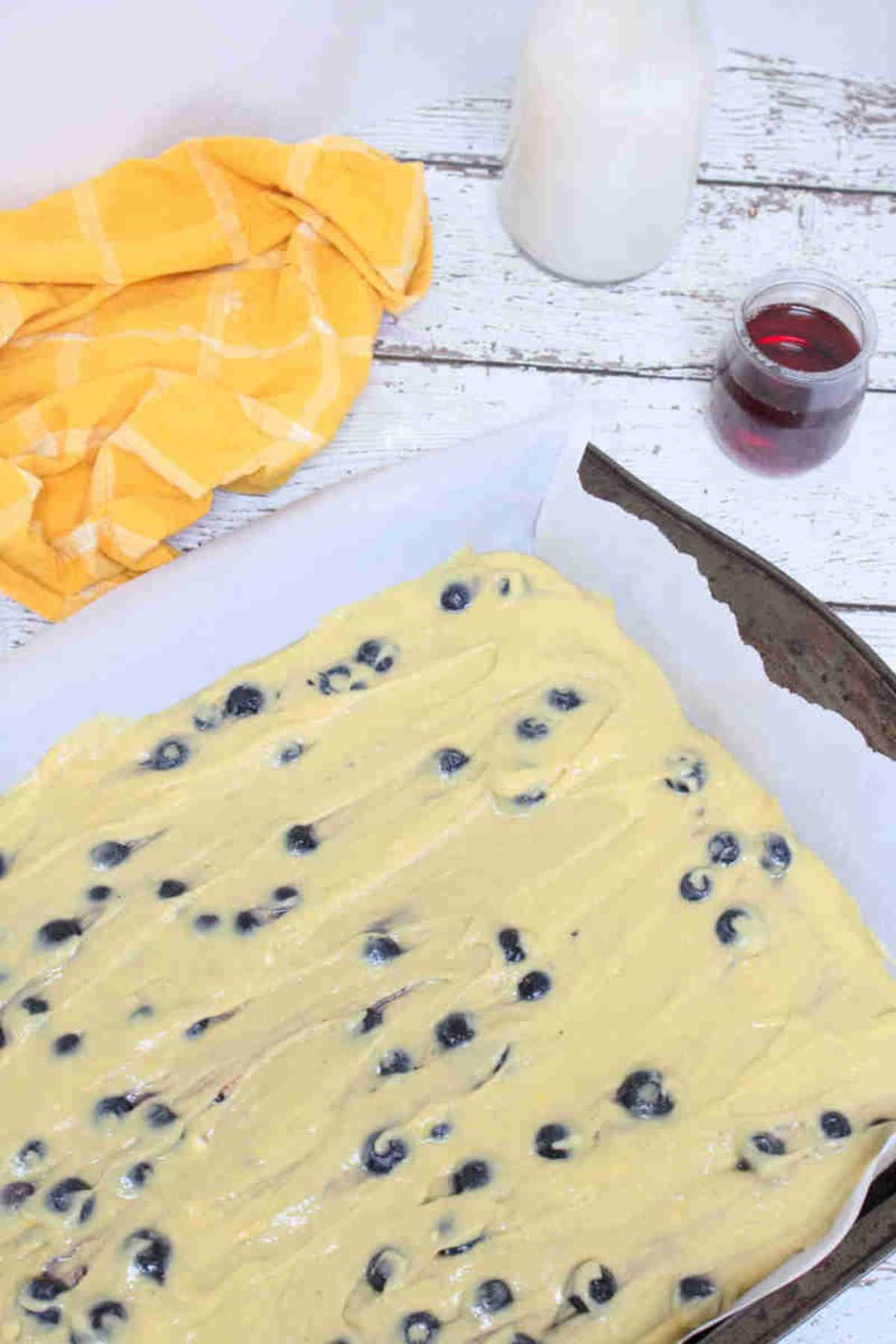 Raw blueberry pancakes on a parchment paper lined baking tray.