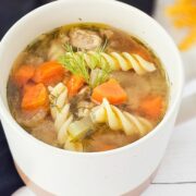 Gluten-free chicken noodle soup in a white cup.