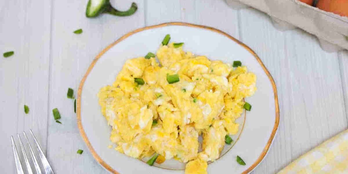 Dairy-free scrambled eggs on a white plate with jalapenos.