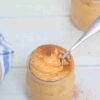 Pumpkin protein pudding in a jar topped with cinnamon and a spoon in the jar.