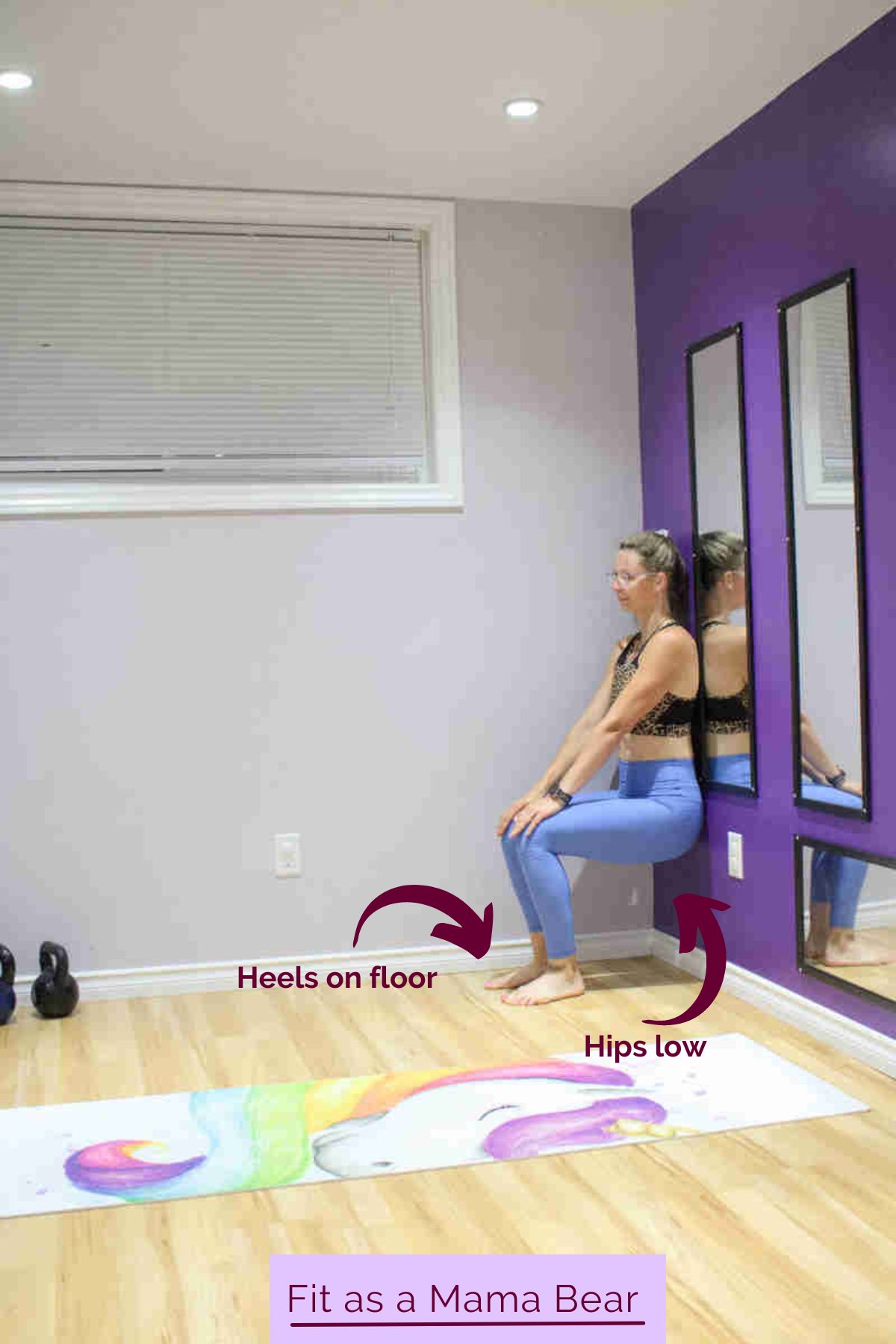 A woman in blue pants and sports bra performing a wall sit.