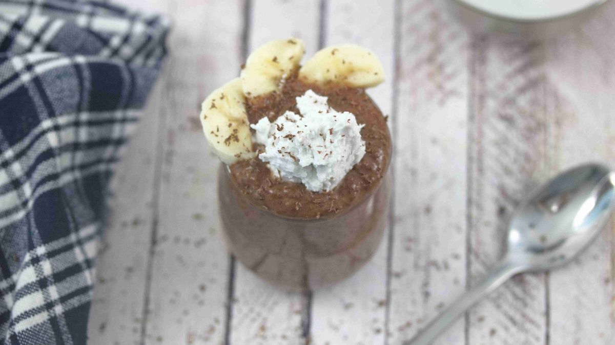 Chocolate chia pudding in a jar with whole30 whipped cream and bananas on top.