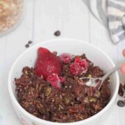 White bowl with chocolate granola in it topped with strawberries.