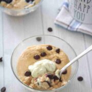Glass bowl with a protein mug cake topped with chocolate chips and a dollop of whipped cream and a spoon in the bowl.
