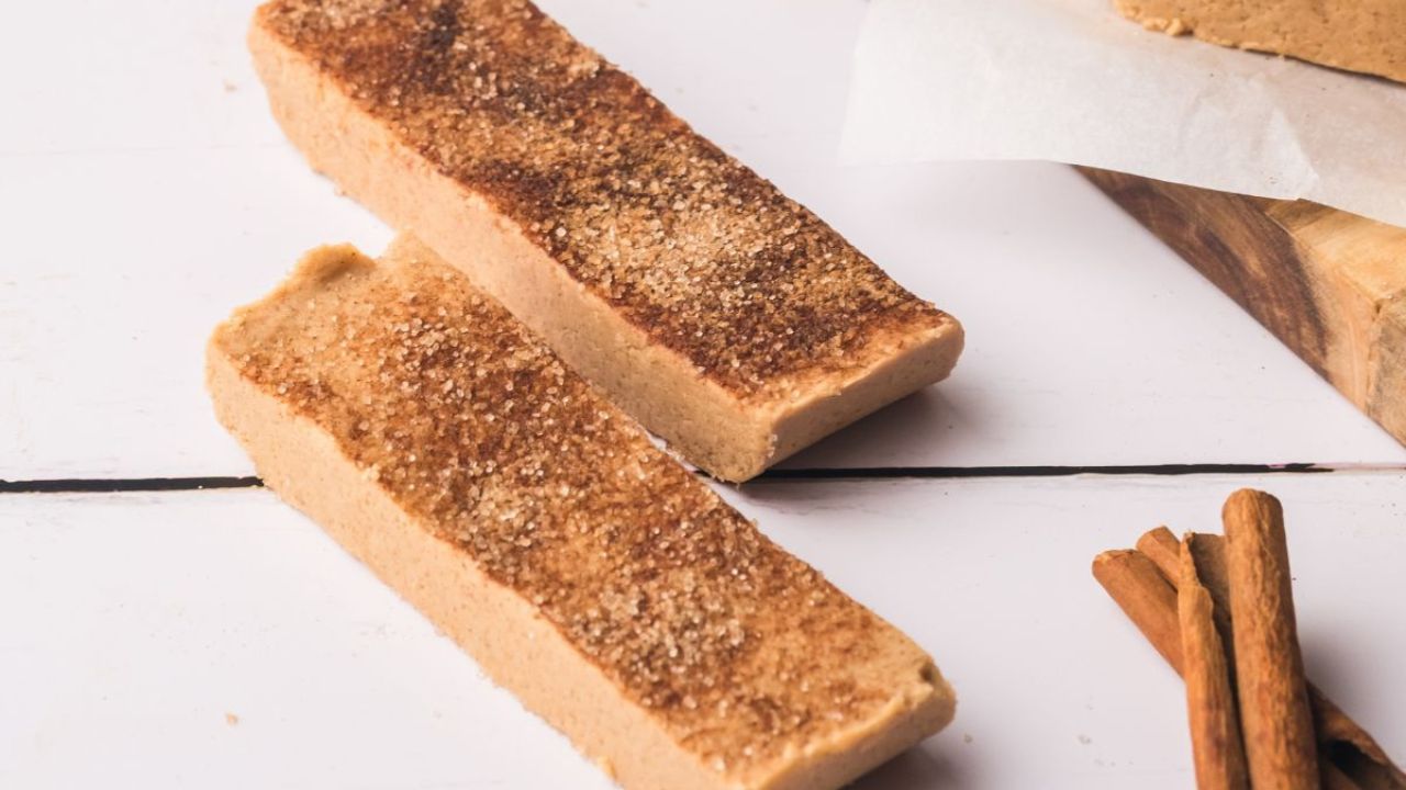 Two snickerdoodle protein bars dusted with cinnamon sugar.