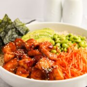 air fried salmon bites with carrots, avocado, edamame, seaweed on top of a bowl of rice