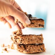 Hand stacking a cookie dough bar on top of two other squares.