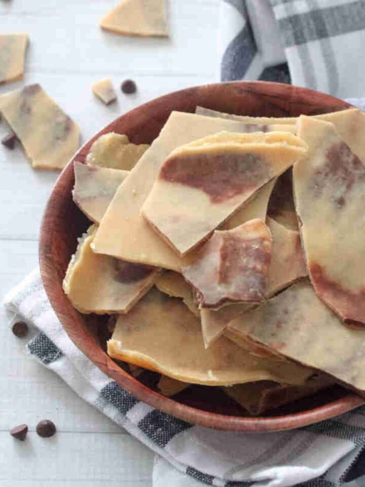 broken pieces of protein peanut butter barks on a plate on top of a kitchen towel