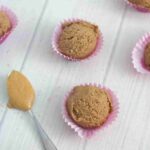 chocolate peanut butter protein balls with a spoonful of peanut butter at the side