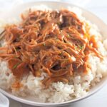 Paleo honey garlic chicken shredded on white rice in a bowl.